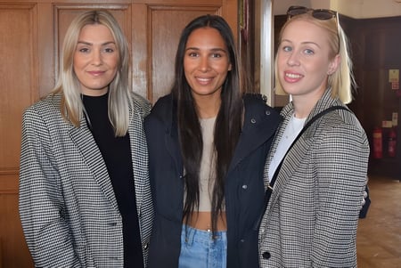Tres alumnas están frente a una puerta de madera en el campus de St. Teresa’s College.