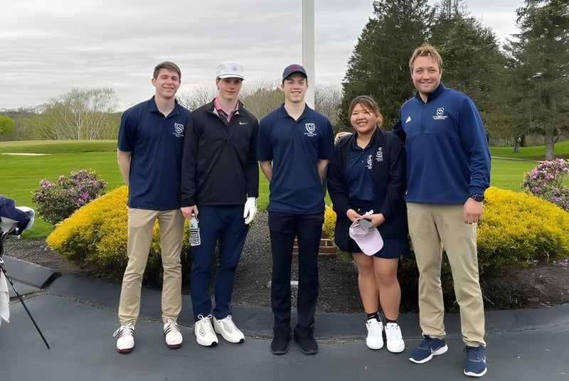 Un grupo de estudiantes de la St. Thomas More School está juntos en el parque con árboles y áreas verdes de fondo.
