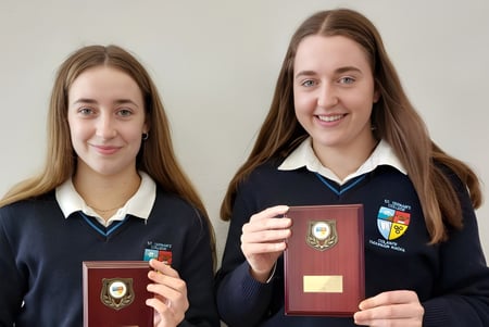 Dos alumnas de St. Tiernan’s College sostienen premios y sonríen a la cámara.
