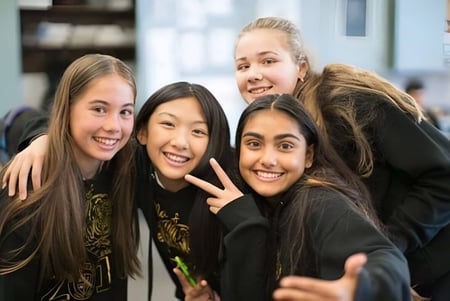Un grupo de estudiantes sonrientes posa juntos en el campus de la St. Timothy High School.