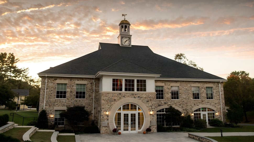 El edificio histórico con reloj en el campus de la St. Timothy's School frente a un cielo de atardecer.