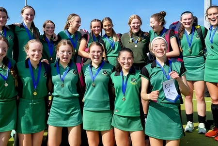Un grupo de jóvenes atletas de la St. Vincent's Secondary School celebra su éxito bajo un cielo azul claro.