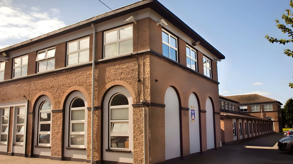El edificio de ladrillo de varios pisos de la St. Vincent's Secondary School en Dublín con arcos en las ventanas y rodeado de árboles.