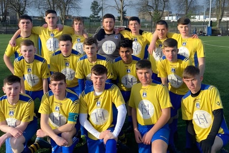 Un grupo de estudiantes masculinos de la St. Vincent's Secondary School en Dublín posan con camisetas amarillas y azules en un campo de deportes.