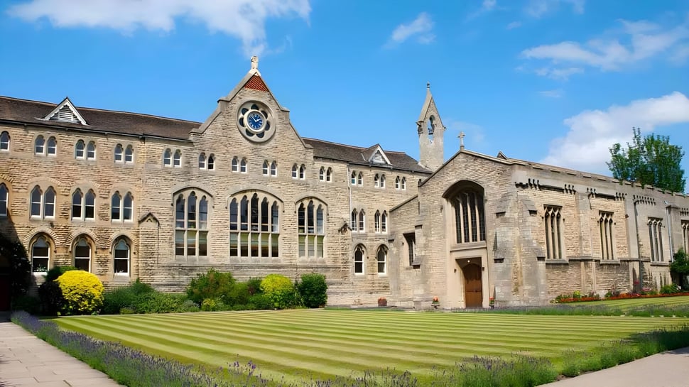 El histórico edificio principal de Stamford Endowed Schools con un campanario y un jardín bien cuidado en primer plano.