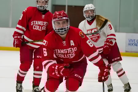 Un grupo de hockeyistas en uniformes rojos y blancos sobre el hielo del Stanstead College.