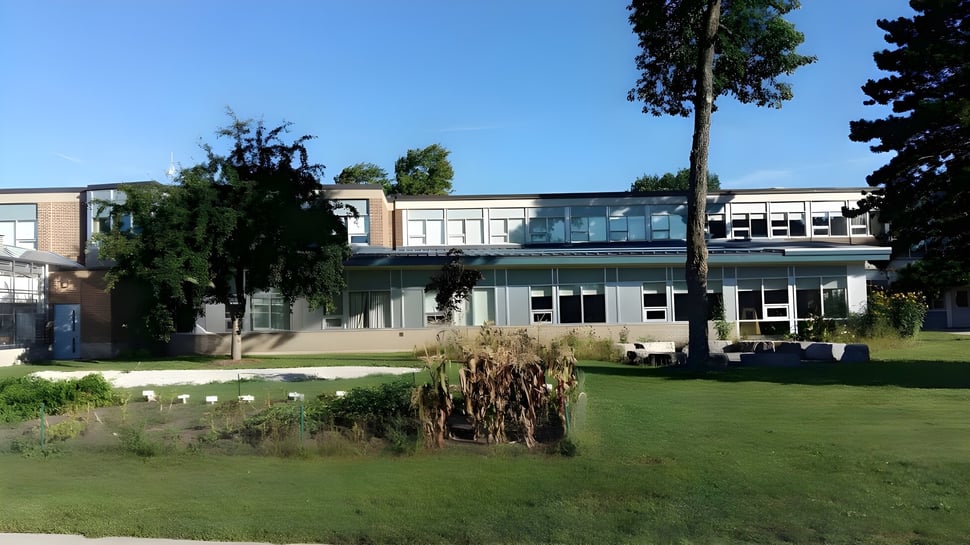 El moderno edificio del Stayner Collegiate Institute está rodeado de césped cuidado y árboles en primer plano.