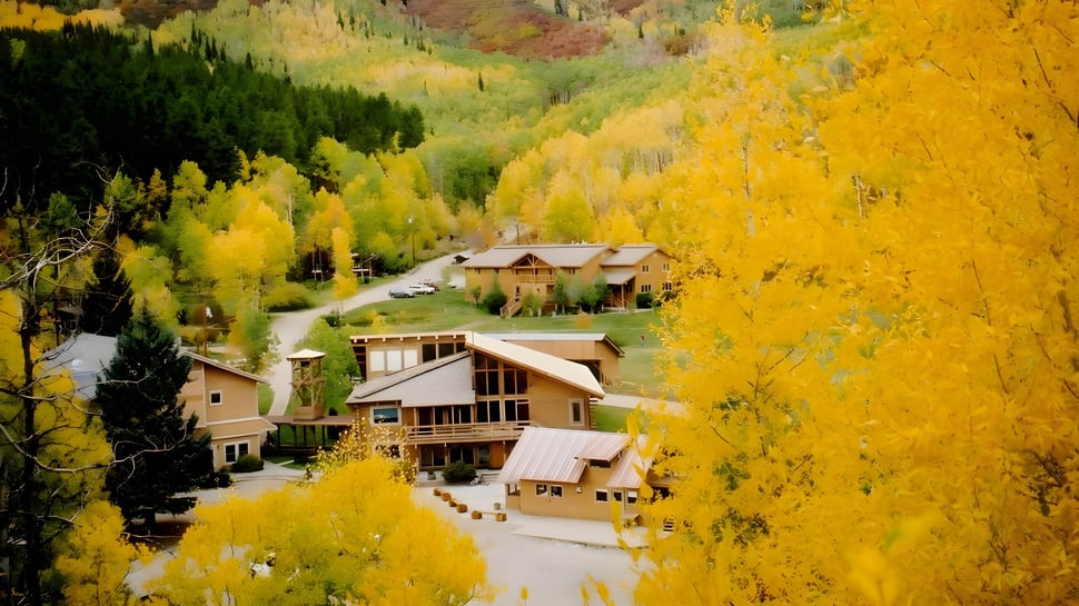 Un pintoresco paisaje montañoso con hojas de colores y una carretera sinuosa cerca de la Steamboat Mountain School.