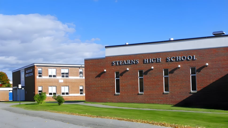 El edificio de ladrillo de la Stearns High School bajo un cielo azul con nubes.