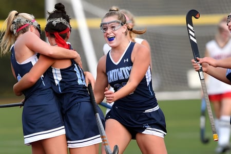 Estudiantes de la Stephen Perse Foundation juegan un partido de hockey sobre césped en un campo de hierba.