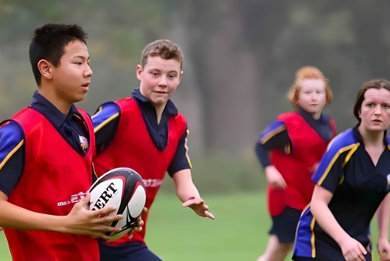 Un grupo de estudiantes en uniformes deportivos juega rugby en el campo de deportes del Stoke College.