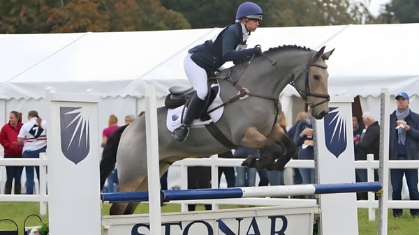Un estudiante de la Stonar School monta al aire libre sobre un obstáculo en una competencia de equitación.
