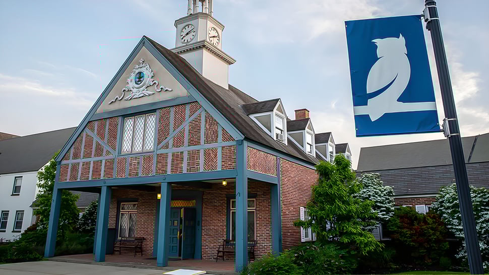 Un edificio histórico de ladrillo con un campanario se encuentra en el terreno de la Stoneleigh-Burnham School rodeado de árboles verdes.