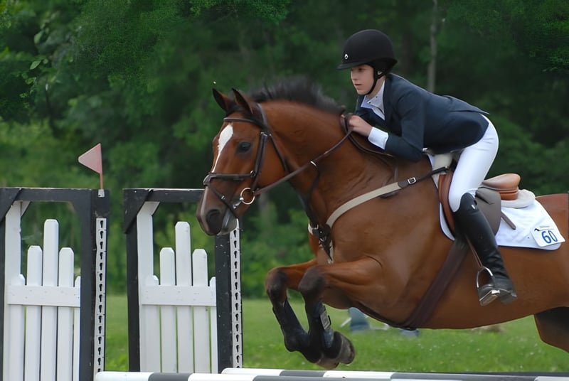 Una estudiante de la Stoneleigh-Burnham School salta con su caballo sobre una valla en un área exterior verde.