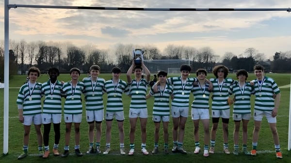Un grupo de jóvenes futbolistas sostiene el trofeo en el campo del Stonyhurst College después de un partido.