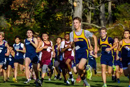 Estudiantes de la The Storm King School corren en una carrera de campo a través por un bosque otoñal.