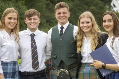 Cinco estudiantes del Stratford College están juntos en un área boscosa cubierta de hierba.