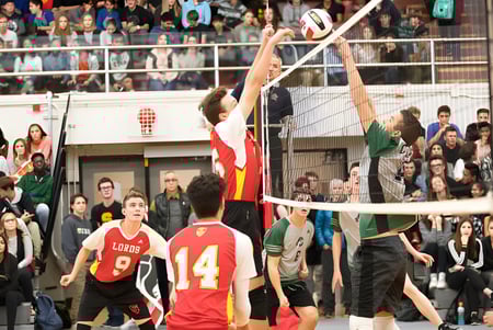Un grupo de estudiantes de la Strathcona High School juega al voleibol frente a espectadores en el gimnasio.