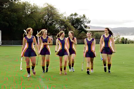 Un grupo de estudiantes en uniformes deportivos está en un campo verde en el Stretton State College.