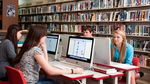 Un grupo de jóvenes estudiantes trabaja en computadoras en la biblioteca de la Stuart Hall School.