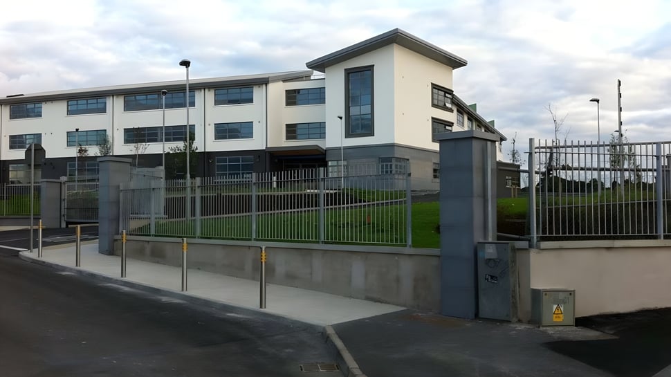 El moderno edificio de varios pisos con entrada y área de césped en el campus del Summerhill College bajo un cielo nublado.