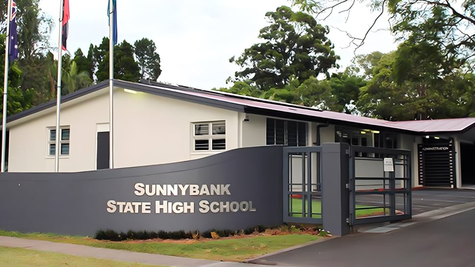 El moderno edificio escolar de la Sunnybank State High School está rodeado de árboles verdes.