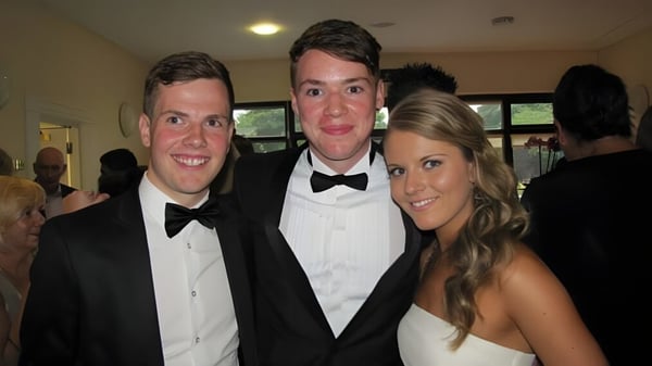 Tres personas vestidas formalmente posan juntas en una celebración en el campus de la Sutton Park School.