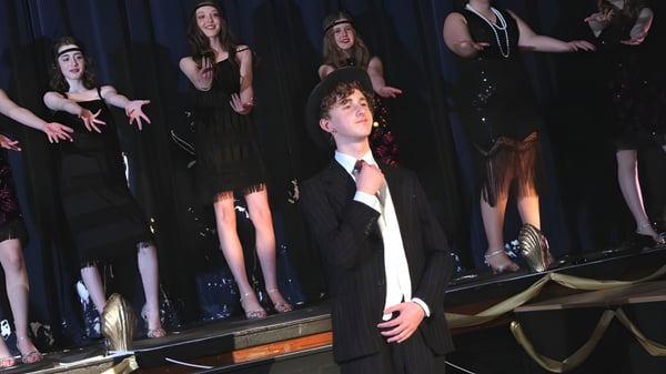 Un grupo de estudiantes de la Sutton Valence School está en un escenario frente a una cortina oscura.