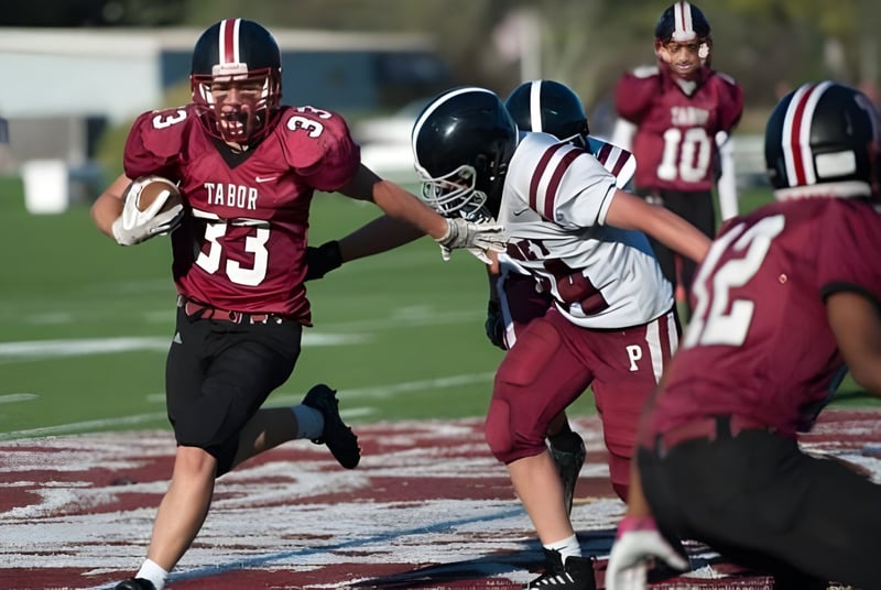 Estudiantes de Tabor Academy juegan un partido de fútbol americano en el campo con ropa deportiva roja y blanca.