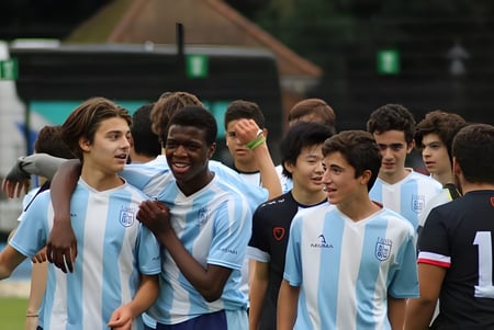 Un grupo de jóvenes futbolistas se reúne en el campo de TASIS The American International School in England.