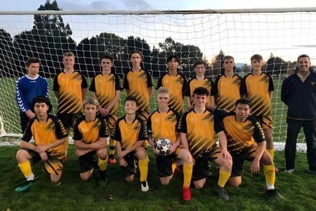 Un grupo de estudiantes posa como equipo de fútbol en el campo del Tauhara College.