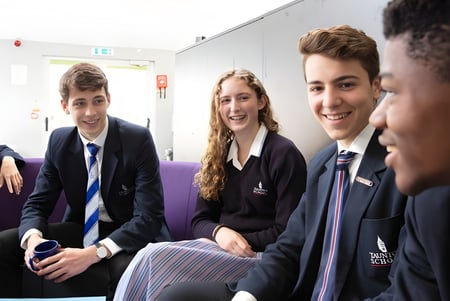 Estudiantes de la Taunton School conversan juntos en el pasillo de la escuela.