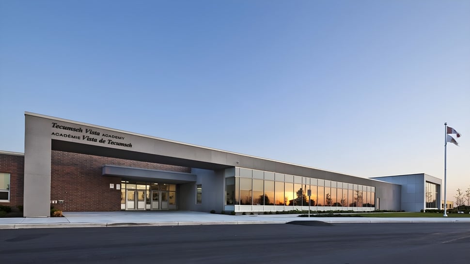El moderno edificio de la Tecumseh Vista Academy con fachada de vidrio y mampostería de ladrillo bajo un cielo despejado.