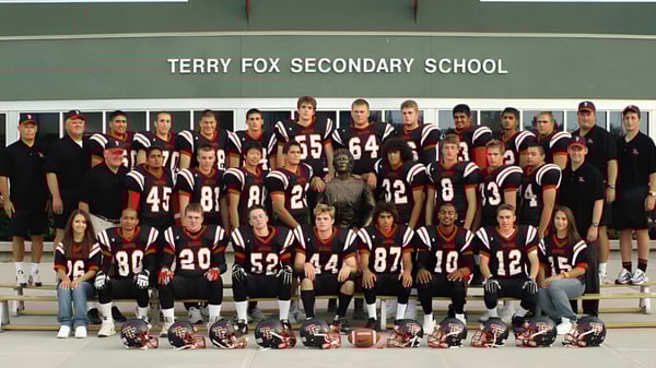 Un grupo de estudiantes de la Terry Fox Secondary School posa frente a un banner con el nombre de la escuela de fondo.