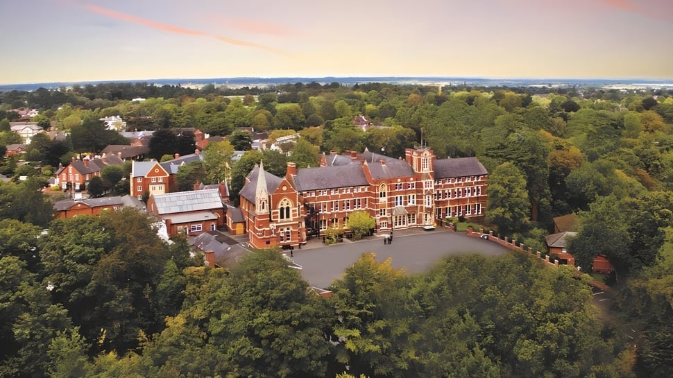 Toma aérea del histórico campus de Tettenhall College con edificios de ladrillo rojo y un entorno verde al atardecer.