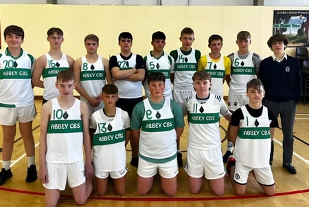 Un grupo de estudiantes de The Abbey School posan juntos en el gimnasio como equipo de baloncesto.