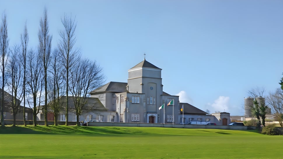 El edificio principal histórico de The Abbey School se encuentra frente a un césped verde con árboles desnudos al fondo.