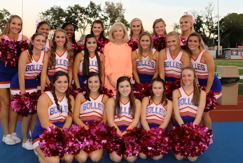 Un grupo de animadoras está en el campo de deportes de The Bolles School con uniformes y pompones uniformes.