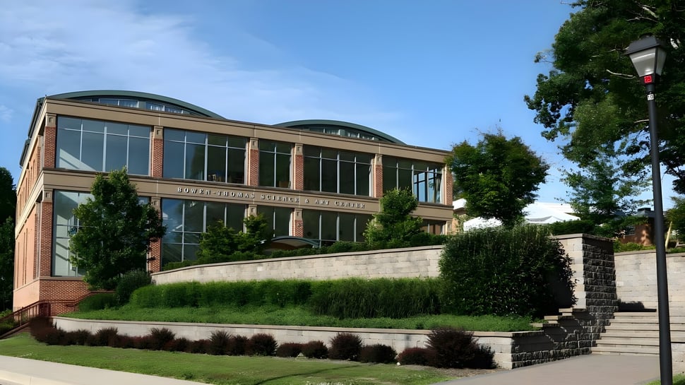 El moderno edificio principal de The Calverton School con grandes ventanas y paisaje verde circundante.