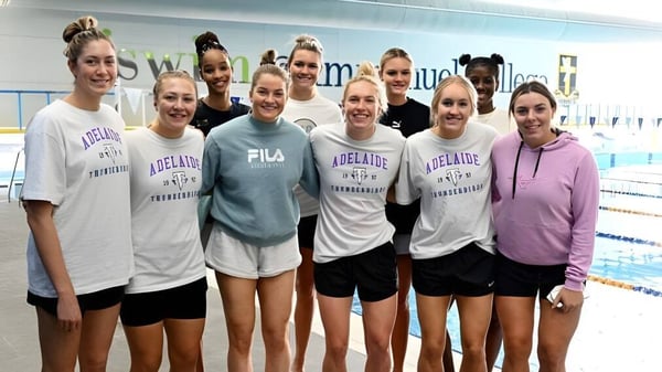 Un grupo de jóvenes estudiantes de The Friends’ School está junto en la piscina con trajes deportivos uniformes.