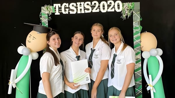 Un grupo de cuatro estudiantes se encuentra frente a un fondo con la inscripción TGSHS2020 en el campus de la The Gap State High School.