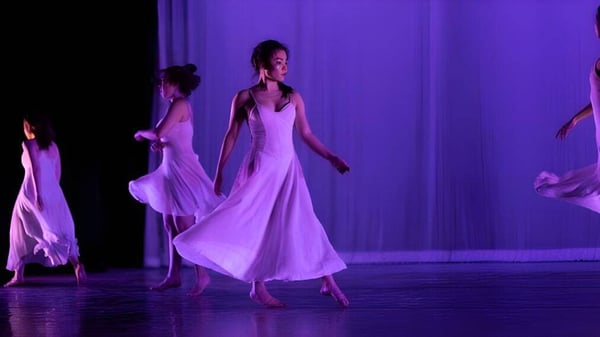 Estudiantes de The Governor's Academy bailan en un escenario frente a un fondo violeta.