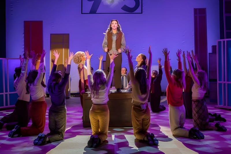 Un grupo de estudiantes está de pie con los brazos en alto en un pasillo de The Hammond School bajo luz violeta.