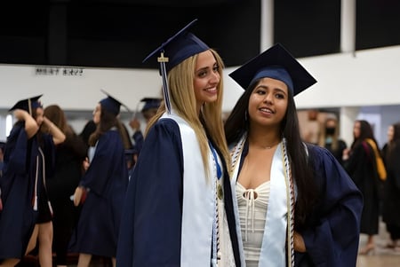 Dos graduadas de The Hills Grammar School están juntas en el salón durante la ceremonia de graduación.