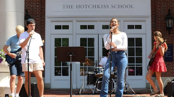 Estudiantes de The Hotchkiss School actúan en un escenario frente al edificio escolar.