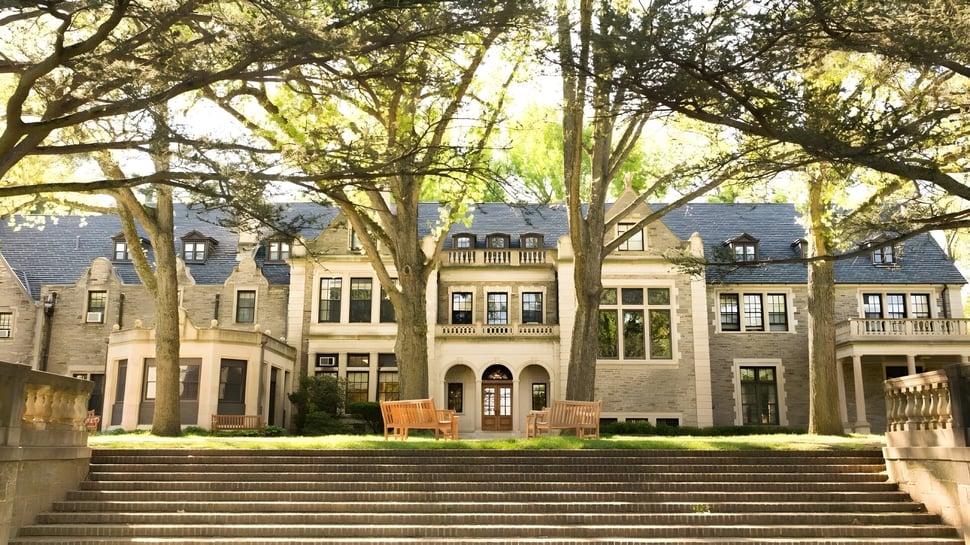 El histórico edificio principal de The Hun School of Princeton rodeado de árboles verdes.