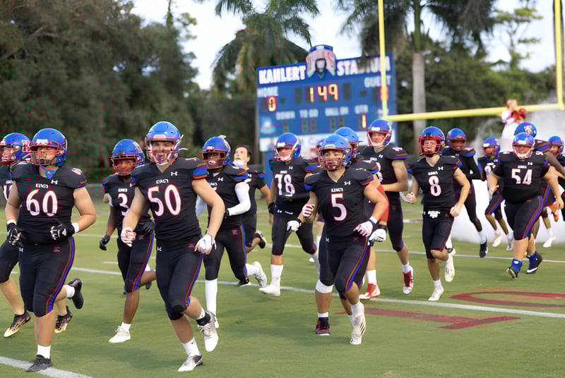 Un grupo de futbolistas en uniforme corre juntos en el campo de deportes de The King's Academy.