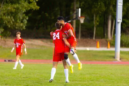 Dos futbolistas con camisetas rojas juegan en el campo deportivo de The Knox School.