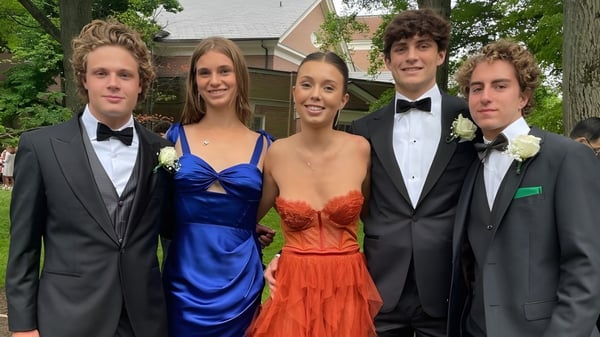 Un grupo de cinco jóvenes vestidos formalmente se encuentra frente a un edificio residencial en el campus de The Lawrenceville School.