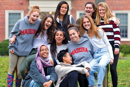 Un grupo de alumnas y alumnos de The Madeira School está riendo frente a un edificio de ladrillo.